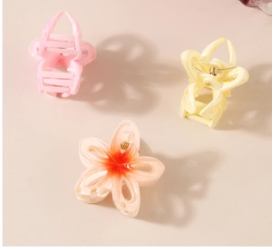 Detailed view of three colorful petal-shaped hair claws in pink, yellow and white resin