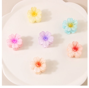 Détail de 6 pinces à cheveux en résine en forme de fleurs colorées sur un plateau blanc