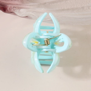 Light blue floral hollow hair claw clip with golden spring on a clean background