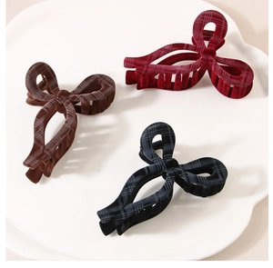 Close-up of velvet bow hair claws in burgundy, brown and navy with plaid texture detail