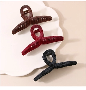 Detail of three large velvet plaid claw clips in dark brown, burgundy, and grey on tray