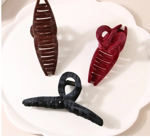Close-up of velvet large hair claw clips in brown, burgundy, and black textured fabric