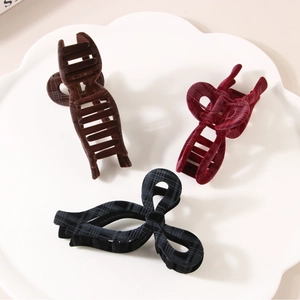 Three elegant checkered and flocked shark hair clips displayed on a white ceramic plate
