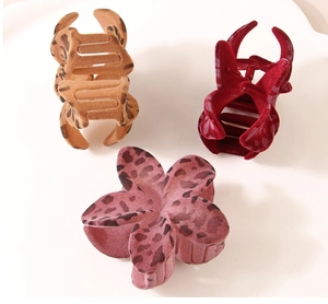 Dettaglio di tre mollette per capelli floccate con stampa leopardata e rosso, stile chic