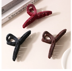 Detailed view of three flocking claw clips in wine red, black, and dark brown colors