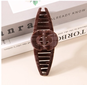 Detail view of coffee brown flocked hair claw with a logo-style oval pattern centerpiece