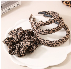 Retro leopard print headband and scrunchie set displayed on a white petal plate