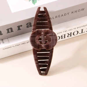 Brown flocked hair claw clip with vintage plaid pattern on a minimalist book background