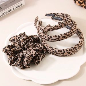 Leopard print headband and scrunchie set with handmade label in a ceramic dish