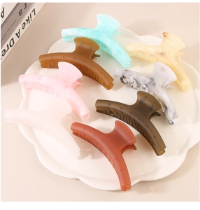 Set of 8 colorful matte acrylic claw clips displayed in a decorative white petal bowl