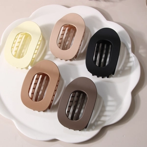 Flat oval matte hair clips in earthy tones displayed in a white decorative tray