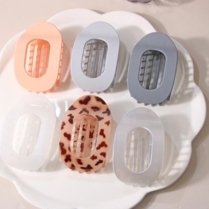 Set of 6 large flat oval hair claw clips in various colors on a decorative ceramic plate