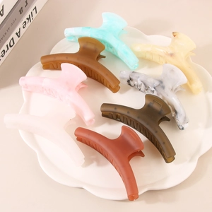 Colorful acrylic shark hair clips in assorted marble patterns displayed on a white tray
