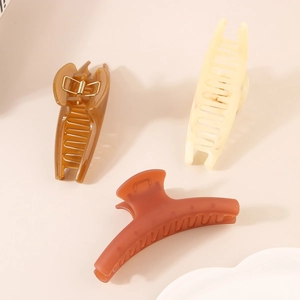 Three large acrylic shark hair claws in amber, beige, and matte reddish-brown tones