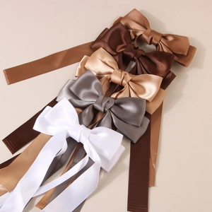 Elegant satin bow hair clips with long streamers in five neutral colors on a beige background
