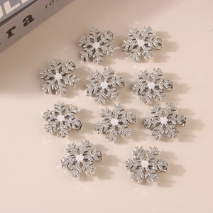 Top view of ten glittering silver snowflake hair clips with pearls on a beige surface