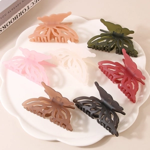 Pinces à cheveux papillon 3D élégantes en sept couleurs mates sur une assiette blanche