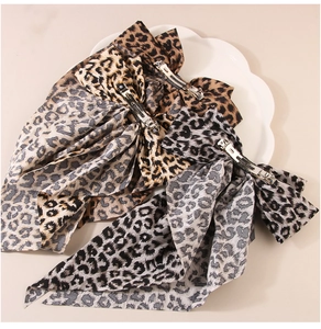 Detailed view of large leopard print bow hair clips with long streamers on a white plate