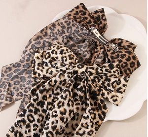 Detail of large leopard print bow hair clips with silver metal spring clips in a tray