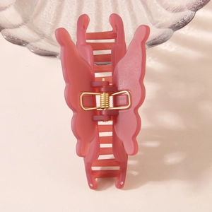 Pince à cheveux papillon rose mat avec ressort en métal doré sur fond beige chaud