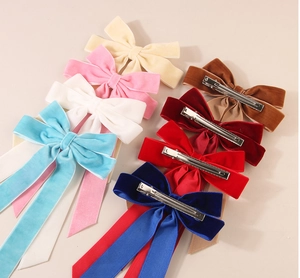Detail of velvet bow hair clips in multiple colors with long ribbons and metal duckbill clips