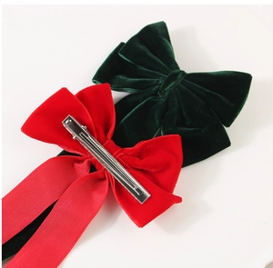 Detail view of red and green velvet bow hair clips with long ribbons and metal duckbill clips