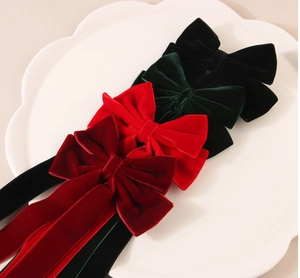 Detailed view of velvet bow hair clips with long streamers in multiple retro colors
