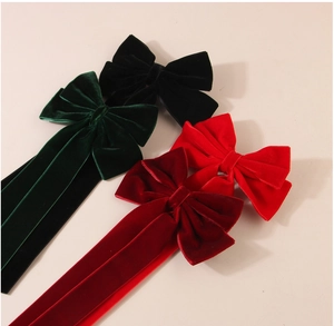 Close-up of velvet bow hair clips with long ribbons in dark green, black, and red colors