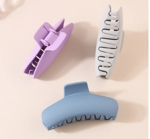 Overhead view of minimalist matte finish hair claw clips in purple, grey, and blue