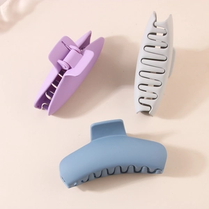 Three large matte plastic shark hair clips in lavender, grey, and blue colors