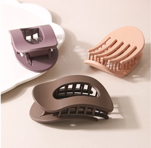 Trois pinces à cheveux mates en violet, orange et marron sur un plateau minimaliste