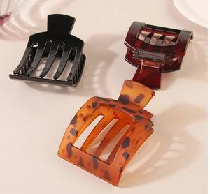 Detailed view of three glossy PC hair claws in black, tortoiseshell, and leopard patterns