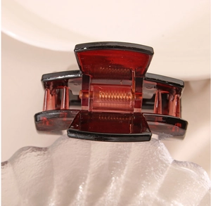Detailed view of square burgundy and black resin hair claw clip with internal metal spring