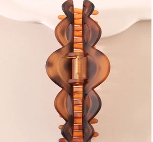 Macro detail of large tortoiseshell hair claw clip with strong golden metal spring