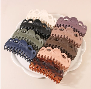 Detailed top view of large French hair claws in various colors on a petal-shaped tray