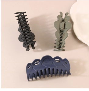 Close-up of matte hair claw clips in black, olive green, and navy blue with interlocking teeth