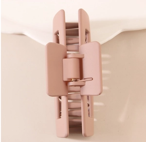 Macro shot of matte pink square hair claw clip featuring a strong metal spring