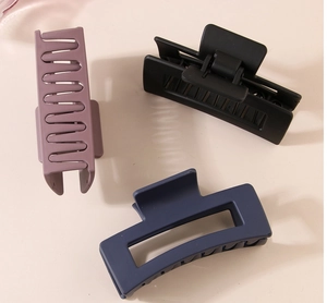 Detail of matte hair clips in pink, black and navy with a rectangular hollow design