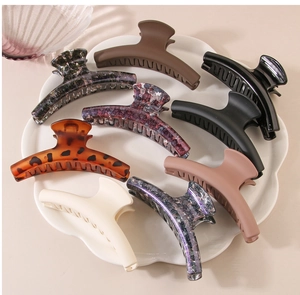 Flat lay of eight colorful resin hair claw clips arranged in a white floral tray