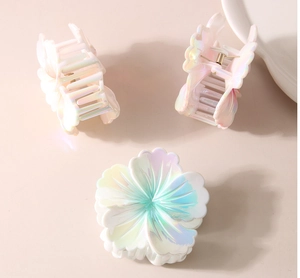 Vue détaillée de grandes pinces à cheveux fleurs avec finition nacrée irisée pastel