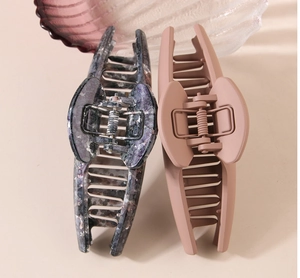Macro shot of large marble grey and matte pink resin hair claws with sturdy metal spring