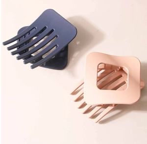 Détail de pinces à cheveux carrées mates en gris foncé et rose nude au design évidé