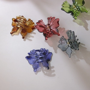 Five butterfly hair claw clips in earth tones on minimalist background with natural shadows