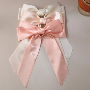 Detailed view of three layered satin bow hair clips in white, pale pink, and coral pink