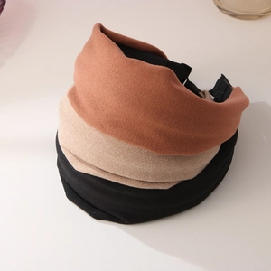 Close-up of wide velvet headbands in black, beige, and brick red with soft texture