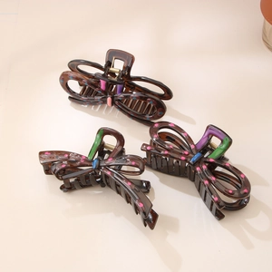 Bow hair claw clips with colorful polka dots and hand-painted patterns on dark resin