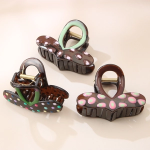Close-up of three colorful polka dot hair claws with sturdy golden metal springs