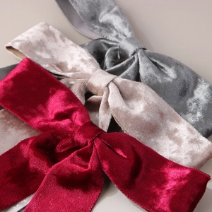 Close-up of three velvet bow hair clips in burgundy, champagne, and grey colors