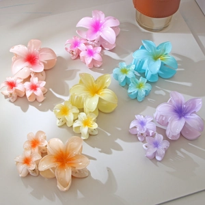 Dettaglio set di tre fermagli per capelli a forma di plumeria in colori sfumati estivi