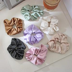 Set of 12 silk satin hair scrunchies in assorted colors displayed with elegant props